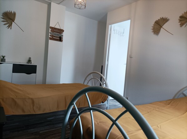 Un dormitorio con dos camas, un escritorio y decoración en la pared.