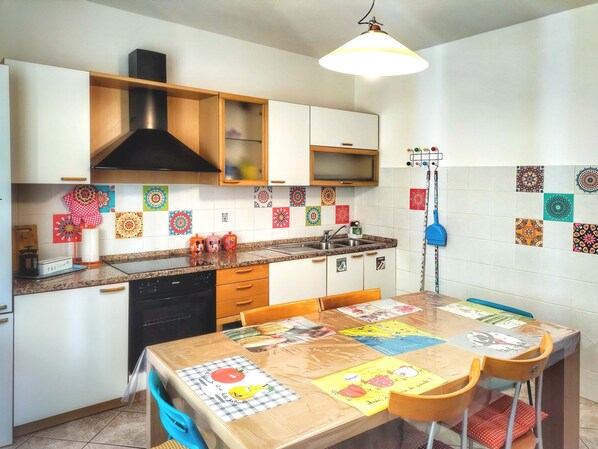 Une cuisine avec des meubles en bois, un poêle noir et une table à manger avec des sets de table pour enfants.
