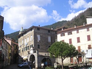 Una calle estrecha con edificios de piedra, una iglesia con cúpula y una montaña al fondo.