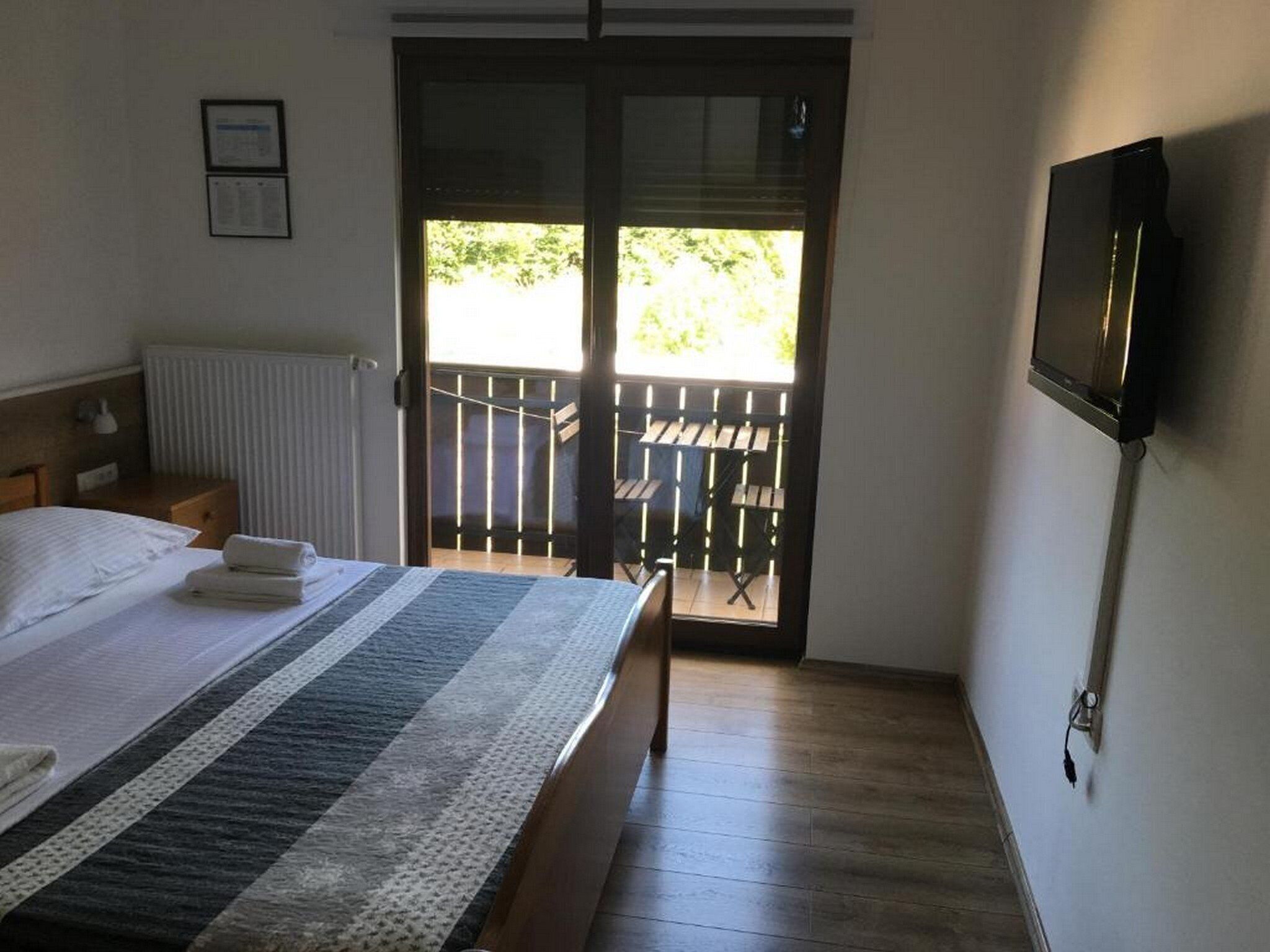 Une chambre d’hôtel avec un lit, un téléviseur fixé au mur et un balcon équipé d’une table et de chaises.