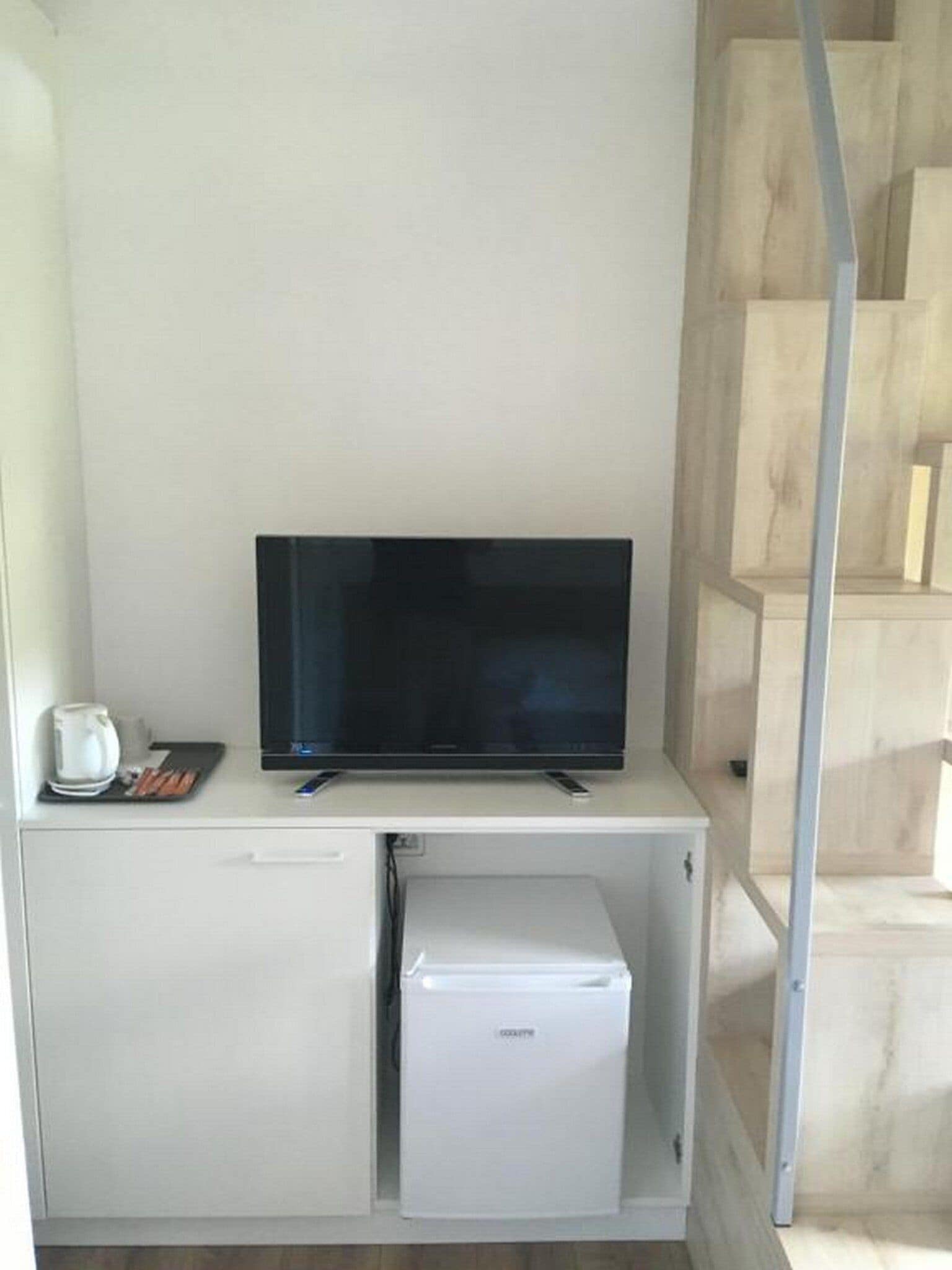 A compact kitchenette with a flat-screen TV, a coffee maker, and a mini-fridge.