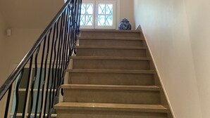A staircase with a black railing, leading to a landing with a window.