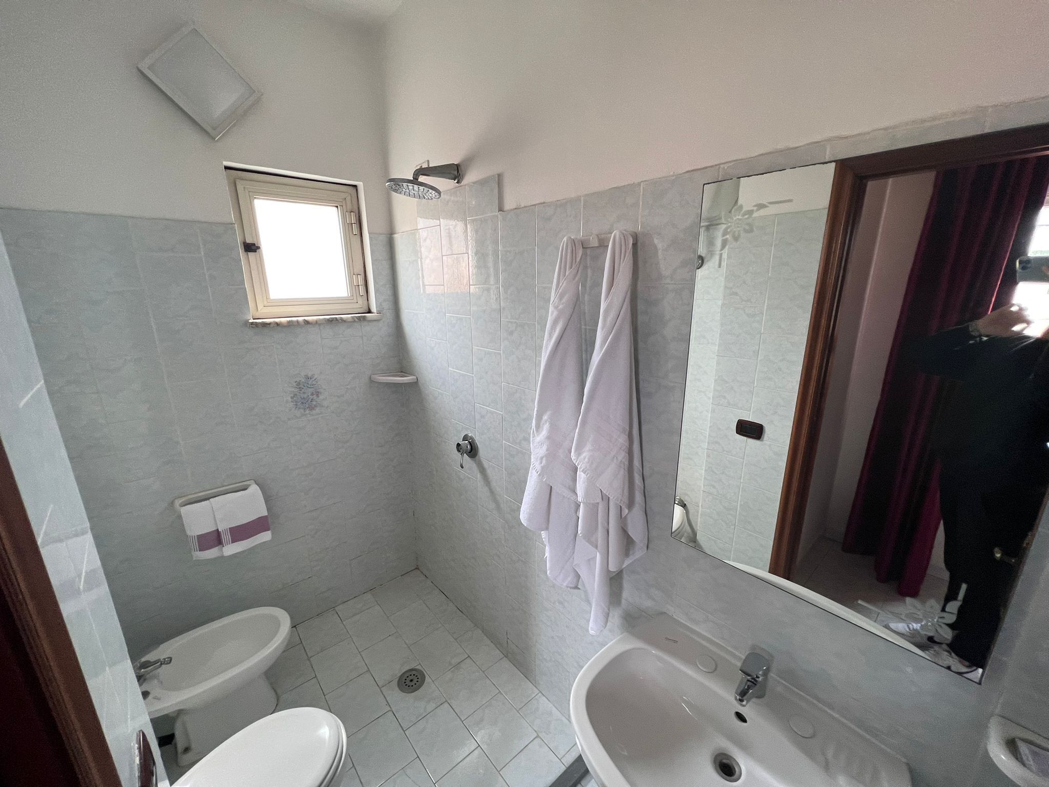 A bathroom with two sinks, a shower, a toilet, and a window.