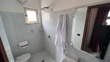 A bathroom with two sinks, a shower, a toilet, and a window.