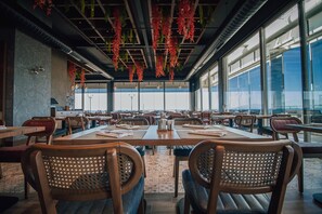 A spacious restaurant with high ceilings, hanging plants, and large windows offering a view. - Panagia Premier Trabzon (Trabzon)
