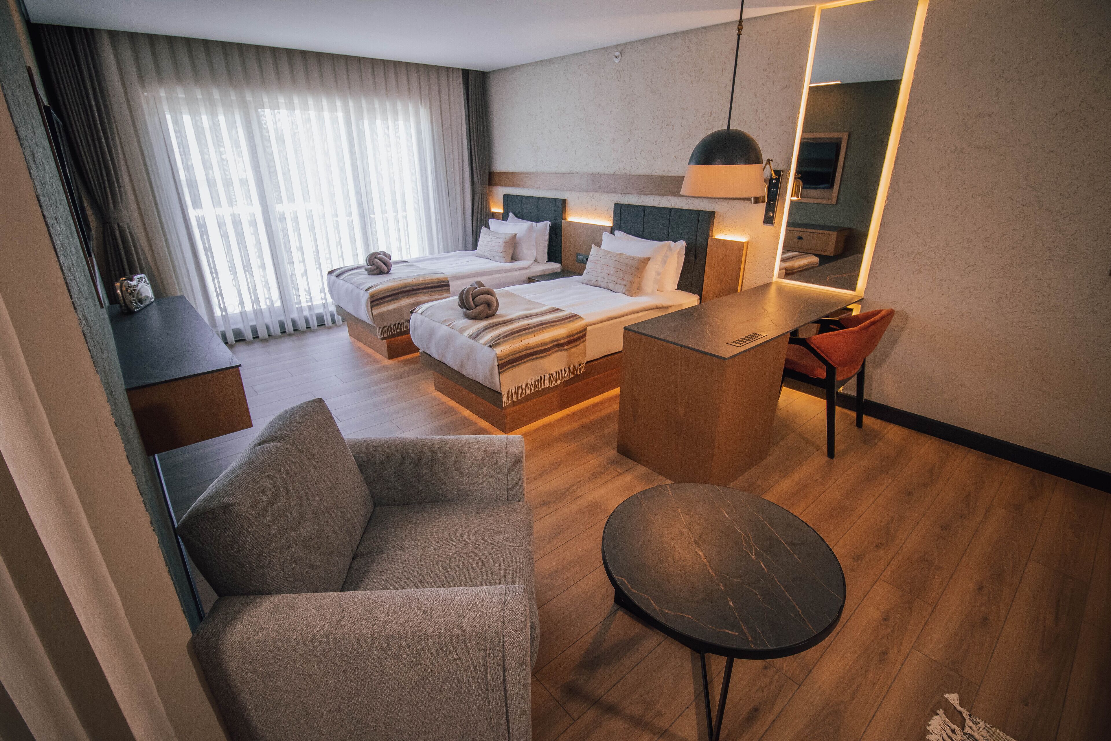A hotel room with two beds, a sitting area, a small table, and a mirror.