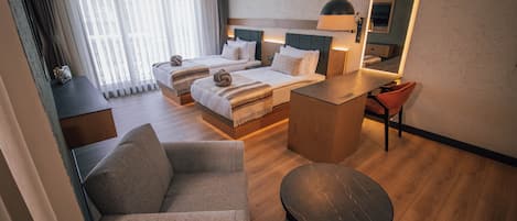 A hotel room with two beds, a sitting area, a small table, and a mirror.