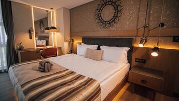 A hotel room with a large bed, a nightstand, a desk, and a mirror.