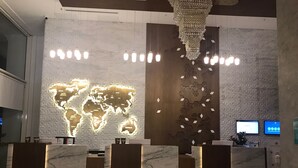 A reception area with a world map illuminated on the wall, a chandelier, and a reception desk. - Panagia Premier Trabzon (Trabzon)