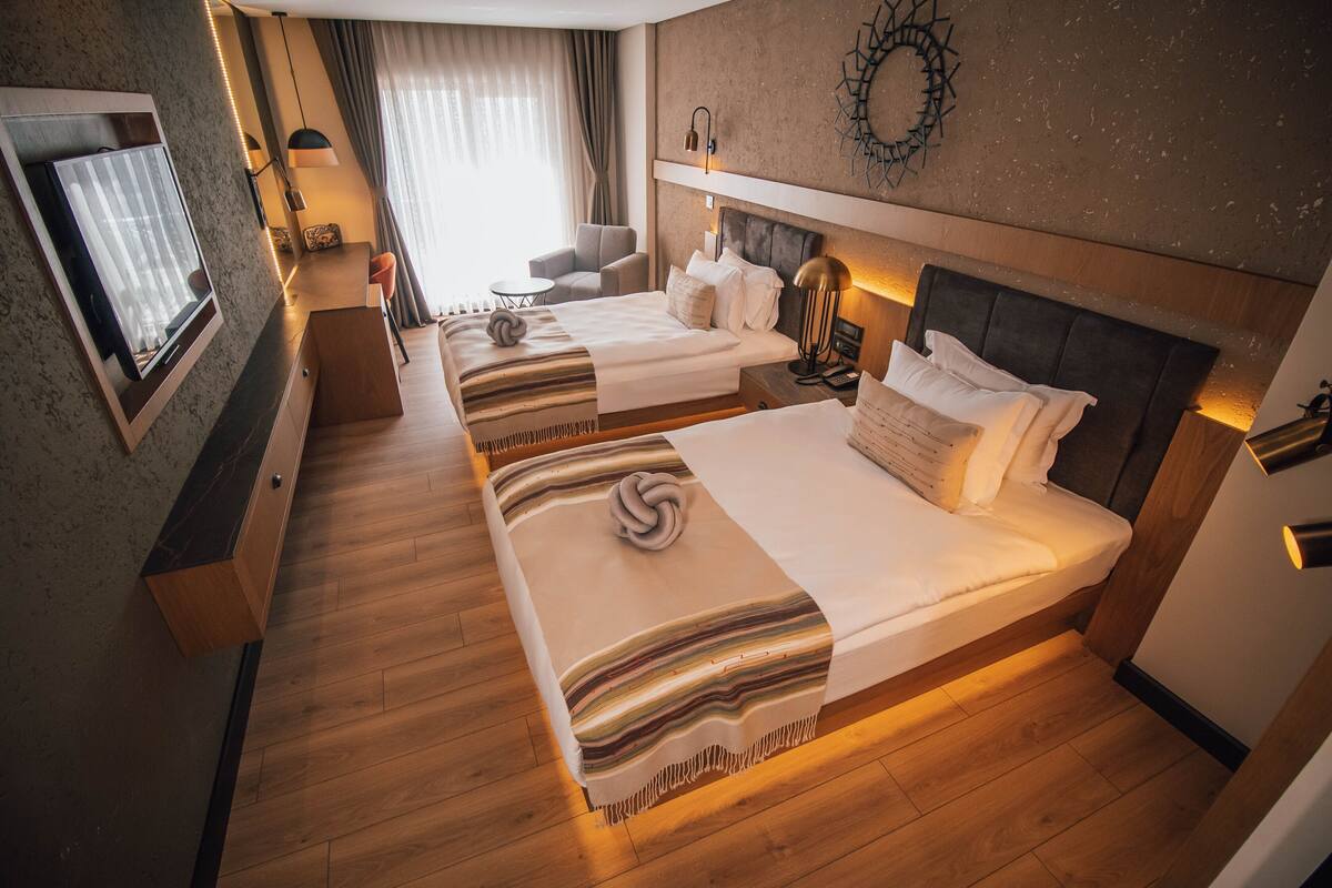 A hotel room with two beds, a TV, a desk, and a chair.