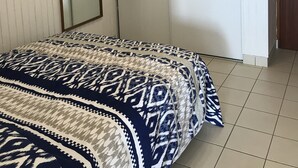 A bedroom with a bed, a large mirror, a door, and a wall-mounted telephone. - Apartment (Saint-Hilaire-de-Riez)