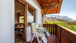 A balcony with wooden railings, a table, and two chairs. - Apartment "Gartenheim Martin" with Mountain View, Pool & Sauna (Scena)