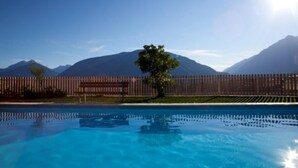 A swimming pool with a wooden fence and mountains in the background. - Apartment "Gartenheim Martin" with Mountain View, Pool & Sauna (Scena)