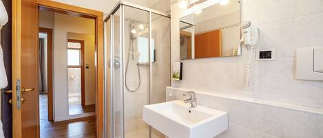 A modern bathroom with a glass shower enclosure, a white sink, and a mirror above it.