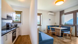 A modern kitchen with a microwave, stove, and cabinets, a dining area with a table and chairs, and a view of the outdoors. - Apartment "Gartenheim Martin" with Mountain View, Pool & Sauna (Scena)