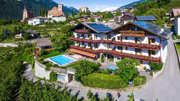 A hotel with a swimming pool, solar panels, and a mountainous backdrop. - Apartment "Gartenheim Martin" with Mountain View, Pool & Sauna (Scena)