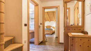 A hallway with wooden shelves, a mirror, and a bed in the background.