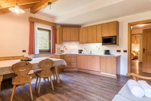 Une cuisine compacte dotée de meubles en bois, d’un four à micro-ondes et d’un coin repas avec deux chaises.