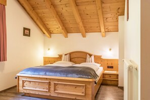 Une chambre à coucher avec un cadre en bois, comprenant un lit, des tables de chevet et un radiateur.