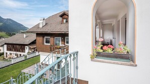 A residential building with a staircase, a window with flowers, and a view of the surrounding landscape. - Apartment 'Prapoz Typ A' with Mountain View, Balcony & Wi-Fi (Ortisei)