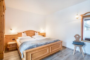 A wooden bed with a headboard, bedside tables, a chair, and a window with a view.