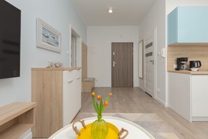 A modern kitchen with wooden cabinets, a coffee maker, and a vase with tulips.