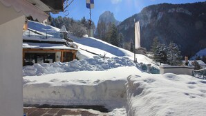 A snow-covered mountain landscape with a building featuring a wooden facade and a snow-covered roof. - Apartment 'Prapoz Typ B1' with Mountain View, Shared Garden & Wi-Fi (Ortisei)