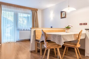 Un espace repas comprenant une table et des chaises en bois, un banc, une plante en pot et une suspension.