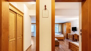 A room with wooden flooring, a bed, a desk, and a television. - Apartment 'Prapoz Typ B2' with Mountain View, Shared Garden & Wi-Fi (Ortisei)