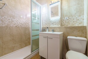 A bathroom with a shower, toilet, and sink, featuring tiled walls and a glass shower door. - Apartment "Carmen" with Terrace & Wi-Fi (Fuengirola)