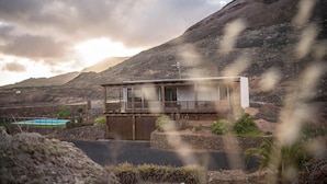 A modern house with a balcony, a pool, and a mountainous backdrop. - Tayu Eco Villa – Mountain Views, Garden & Pool in Villaverde (Villaverde)