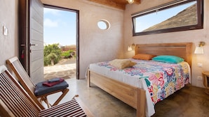 A bedroom with a wooden bed, a bench, a window, and a view of the outdoors. - Tayu Eco Villa – Mountain Views, Garden & Pool in Villaverde (Villaverde)