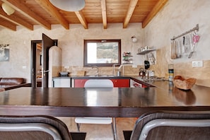 A kitchen with wooden beams, a window, and kitchen utensils hanging on the wall.