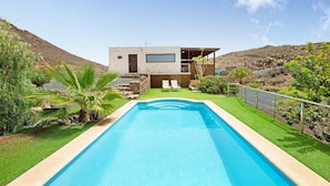 A modern house with a swimming pool, a patio with chairs, and a view of the surrounding landscape. - Tayu Eco Villa – Mountain Views, Garden & Pool in Villaverde (Villaverde)