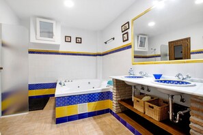 Een badkamer met een bad, twee wastafels en een spiegel.