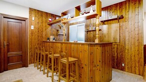 Uma cozinha com painéis de madeira, um espaço bar com banquetas e uma pia embutida.