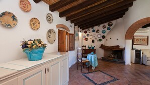 A room with a tiled floor, a wooden ceiling, a fireplace, and various decorative plates on the wall. - Holiday Home "Sa Domedda" with Mountain View, Garden & A/C (Orosei)
