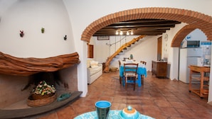 A cozy interior with a fireplace, a dining area, and a kitchen. - Holiday Home "Sa Domedda" with Mountain View, Garden & A/C (Orosei)