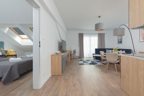 Moderni hotellihuone, jossa on sänky, työpöytä, ruokailutila ja näkymä kaupunkiin.