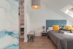 Un dormitorio con cama, mesita de noche, lámpara y estante con toallas dobladas.