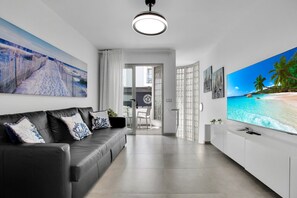 Moderni olohuone, jossa on musta nahkasohva, litteänäyttöinen televisio ja taideteoksia seinillä.