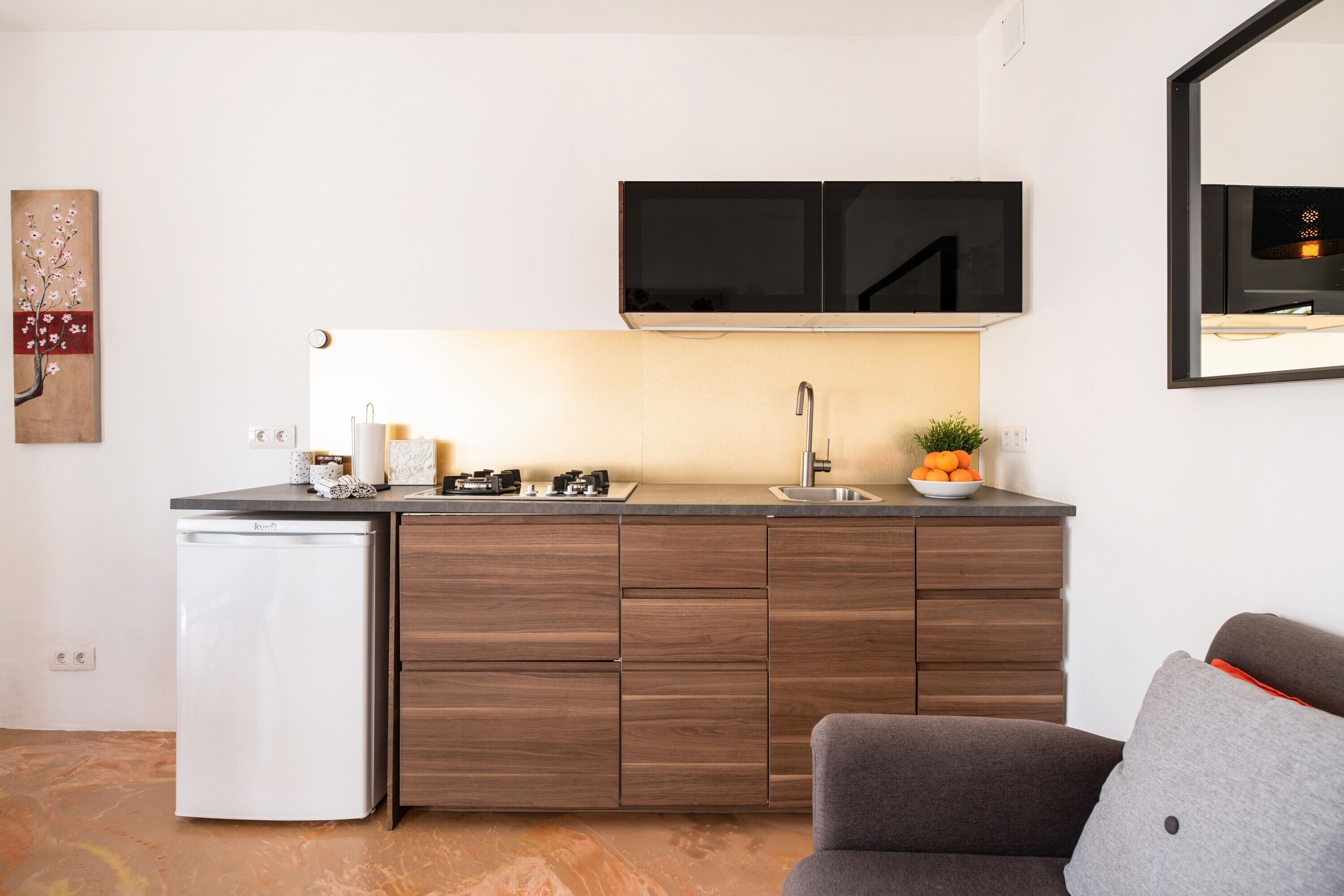 A compact kitchen with a built-in refrigerator, a microwave, and a sink.
