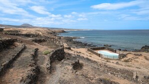 A coastal landscape with stone structures and a pool.