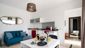 A modern kitchen with a coffee maker, a bowl of cookies, and a vase of flowers on the counter.