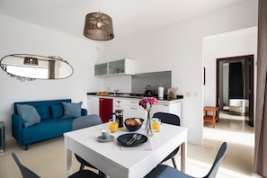 A modern kitchen with a coffee maker, a bowl of cookies, and a vase of flowers on the counter.