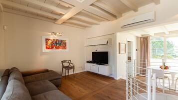 A living room with a sectional sofa, a TV, and a painting on the wall.