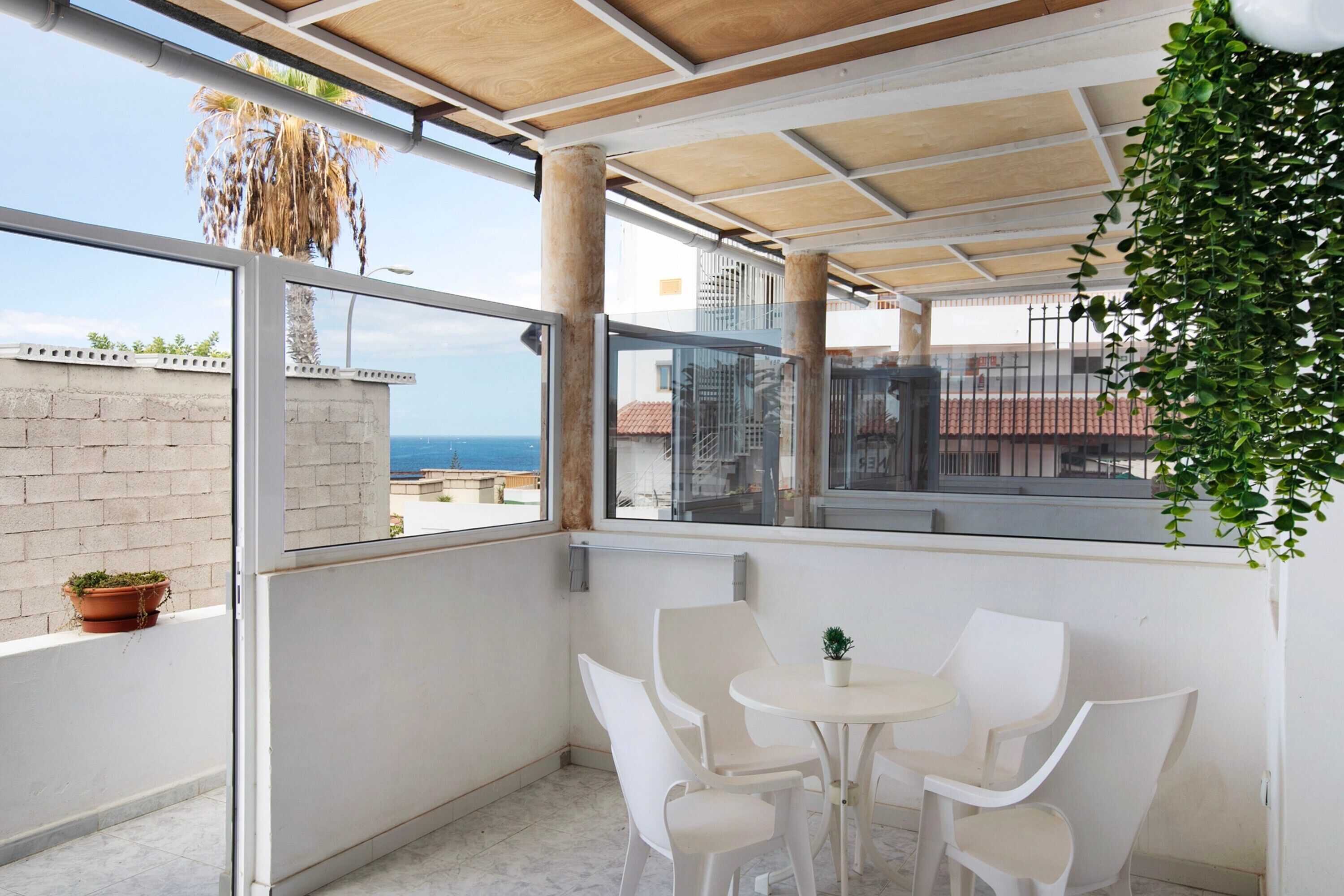 Un balcon avec une table et des chaises, une vue sur la mer et une plante en pot.