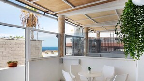 A balcony with a table and chairs, a view of the sea, and a potted plant. - Holiday Home 'Estudio 4 Costa Adeje' with Wi-Fi (Adeje)