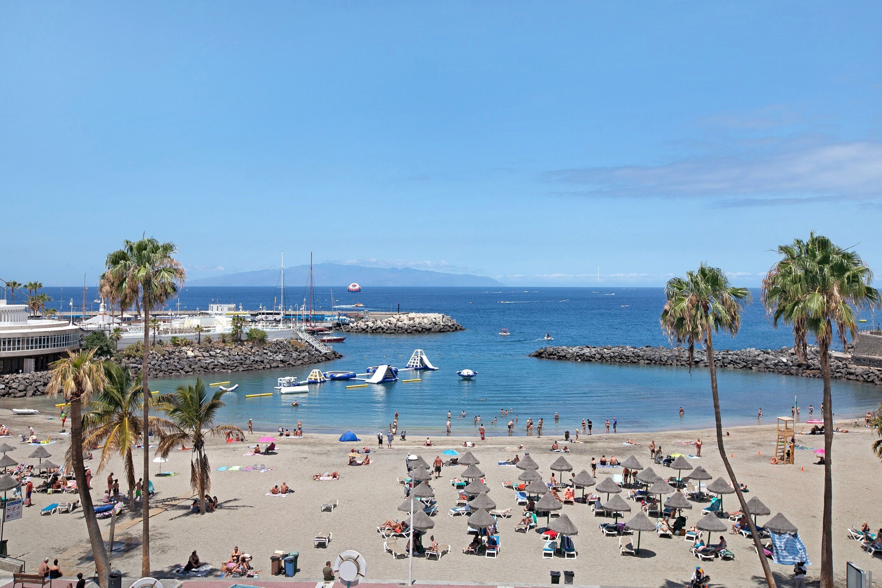 Une plage avec des palmiers, des parasols et des bateaux.