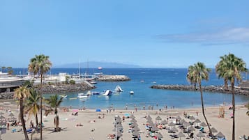 Une plage avec des palmiers, des parasols et des bateaux.